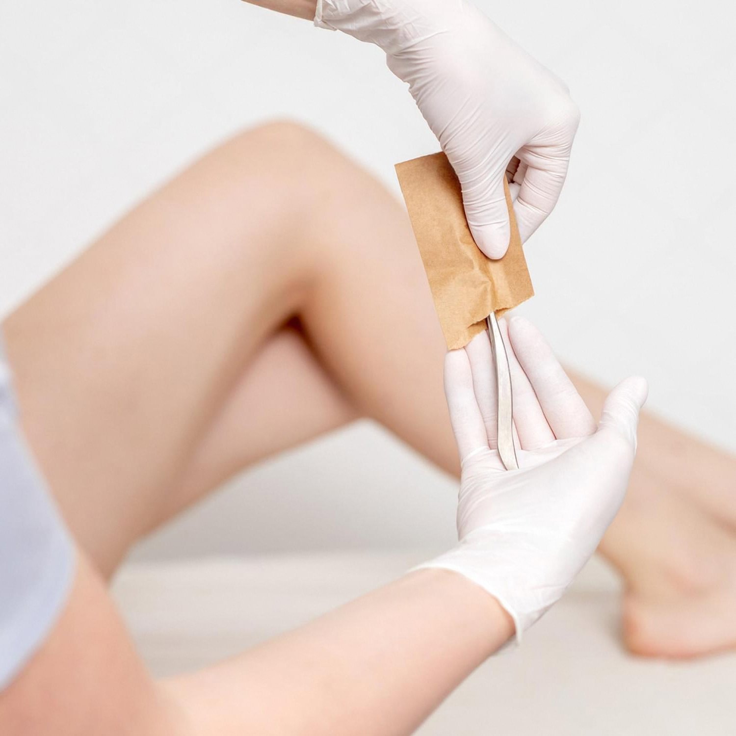 Therapist removing hair from a client's leg with a wax strip during a full body waxing session